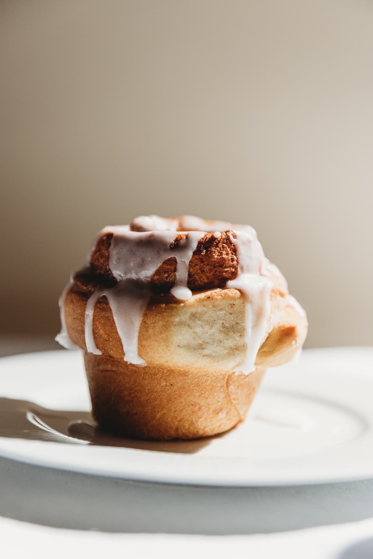 Iced cinnamon roll on a white plate